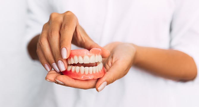 Hands holding full dentures