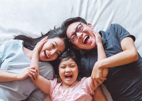 A family three lying in bed laughing