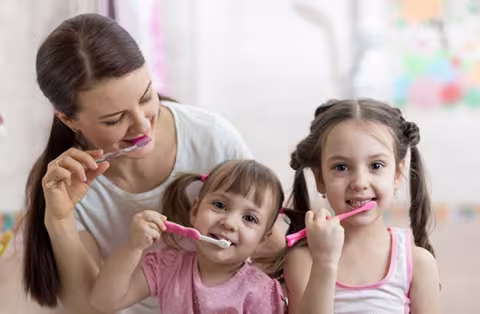Mother two girls brushing teeth