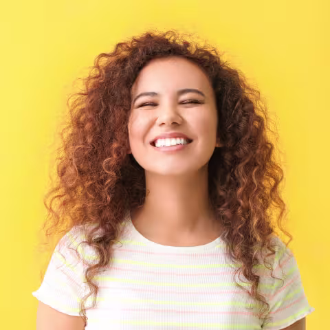 A woman smiling younger, against a yellow background